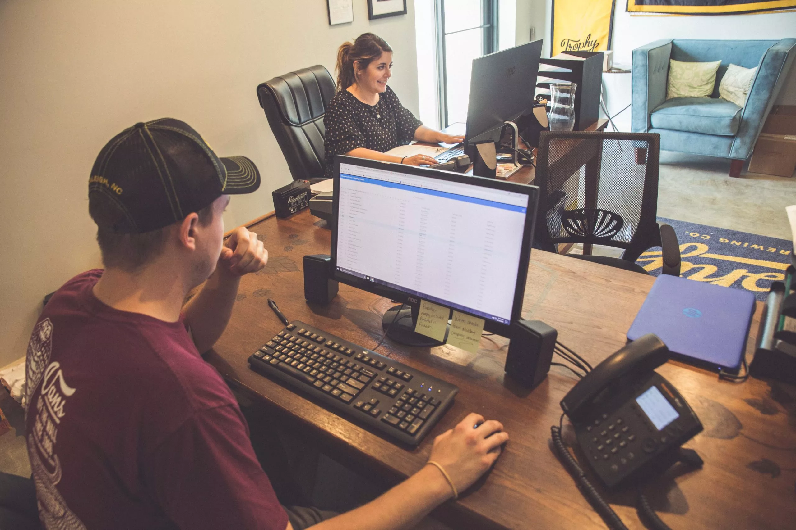 Man and woman sitting at computer looking at brewery cost spreadsheets